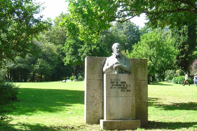 Relvado ao sol, árvores altas e o monumento a João de Barros no Parque Aquilino Ribeiro, em Viseu