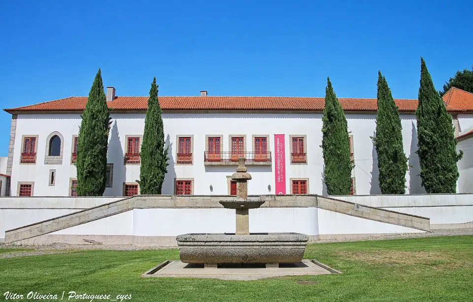 A fachada do Solar do Vinho do Dão, com ciprestes e uma fonte de granito à frente